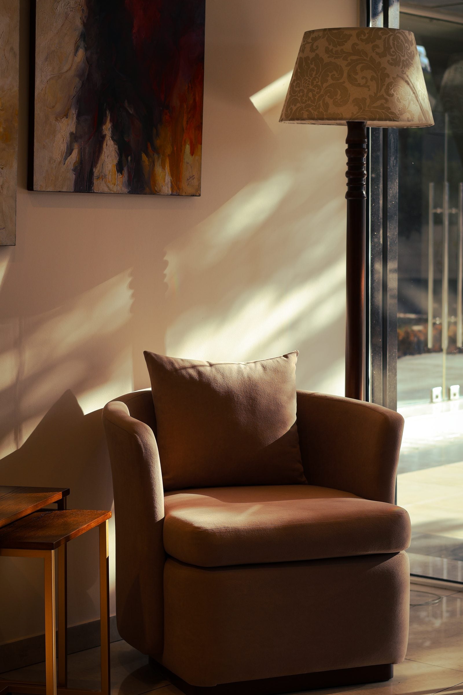 Elegant brown armchair by a window with sunlight casting shadows in a modern interior.