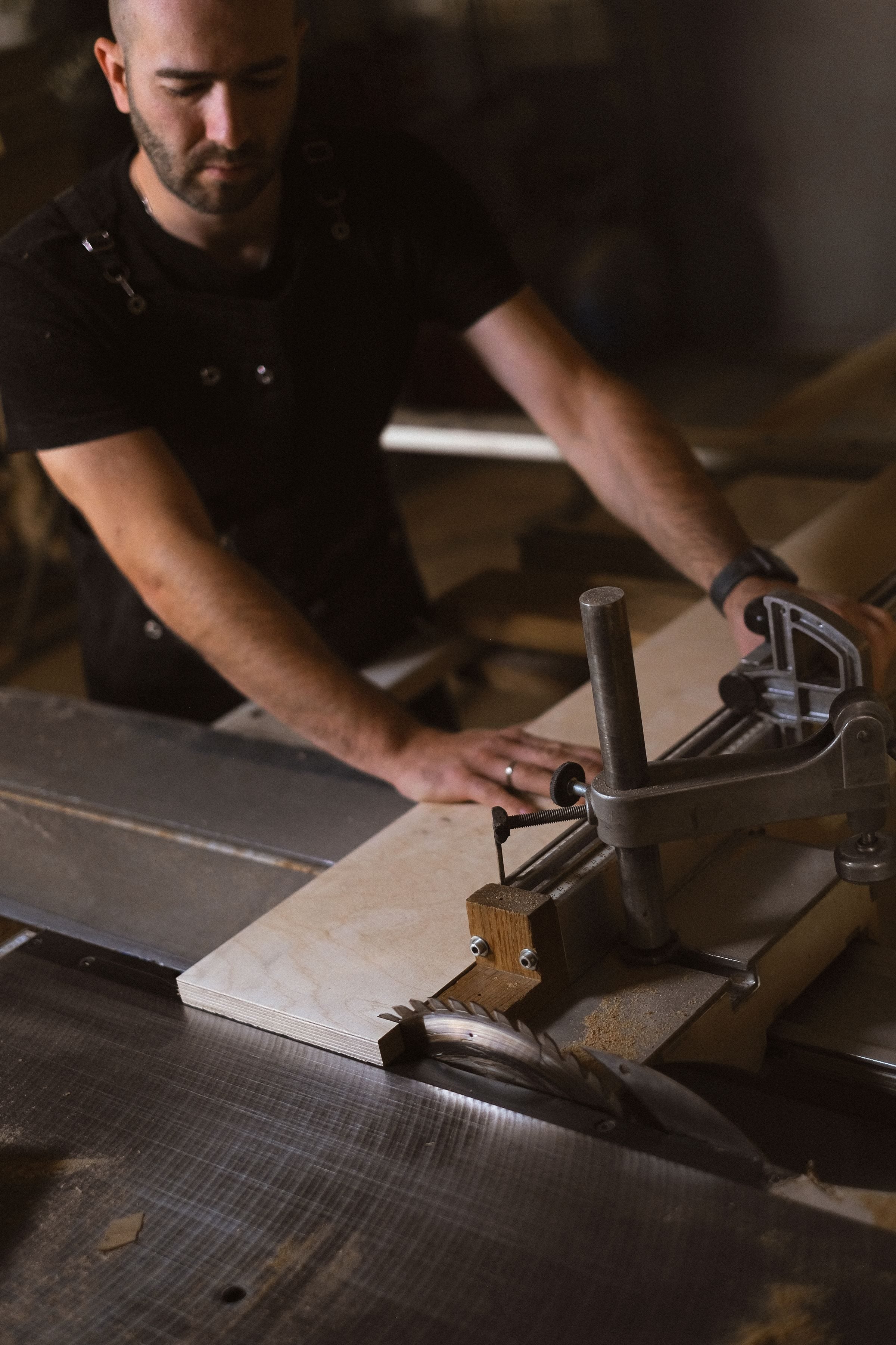 From above of male carpenter working at circular table saw while cutting wooden plank in professional joinery with special equipment