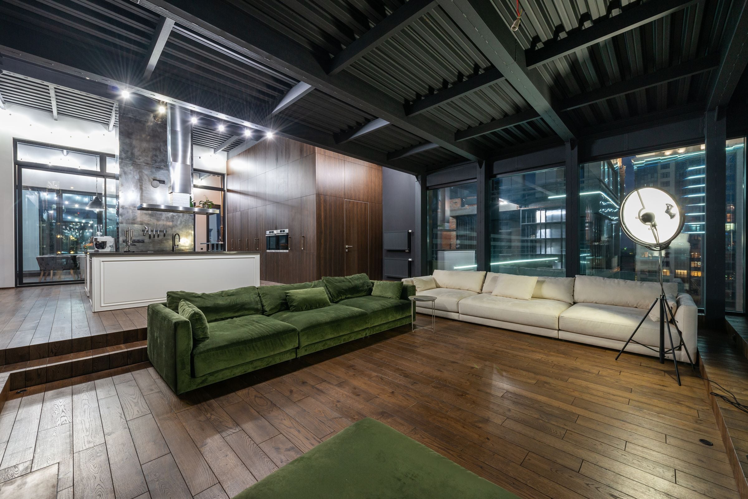 Interior of spacious living room with comfortable sofas and panoramic windows placed in modern flat in evening time