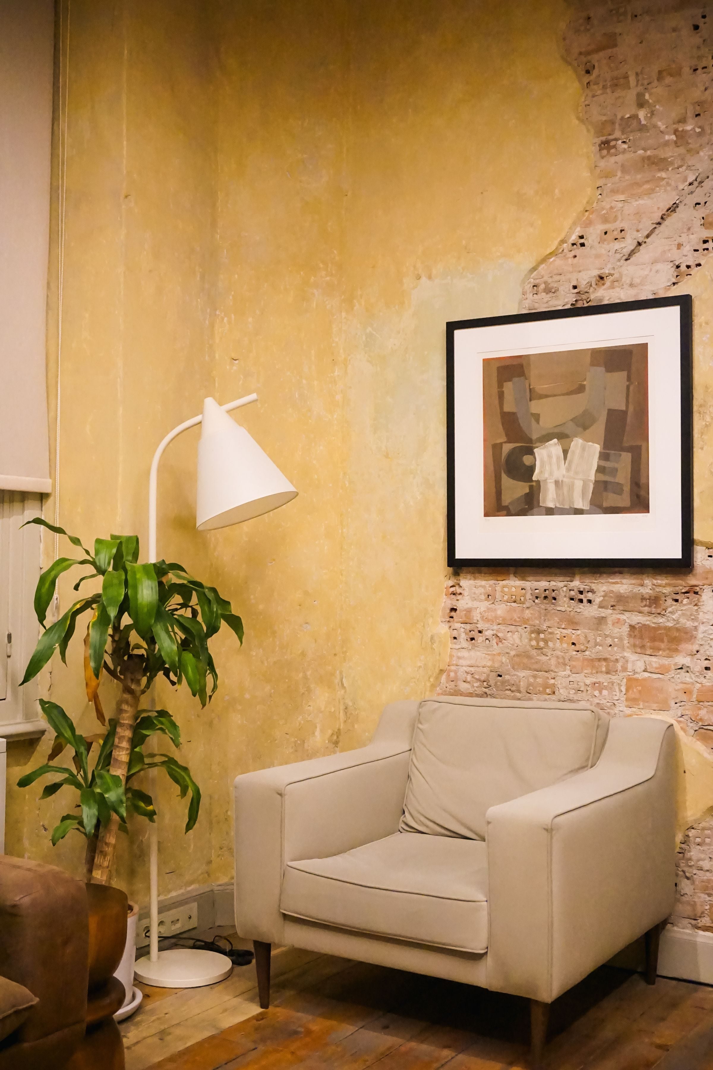 A serene home corner featuring a cozy armchair, lamp, and indoor plant.