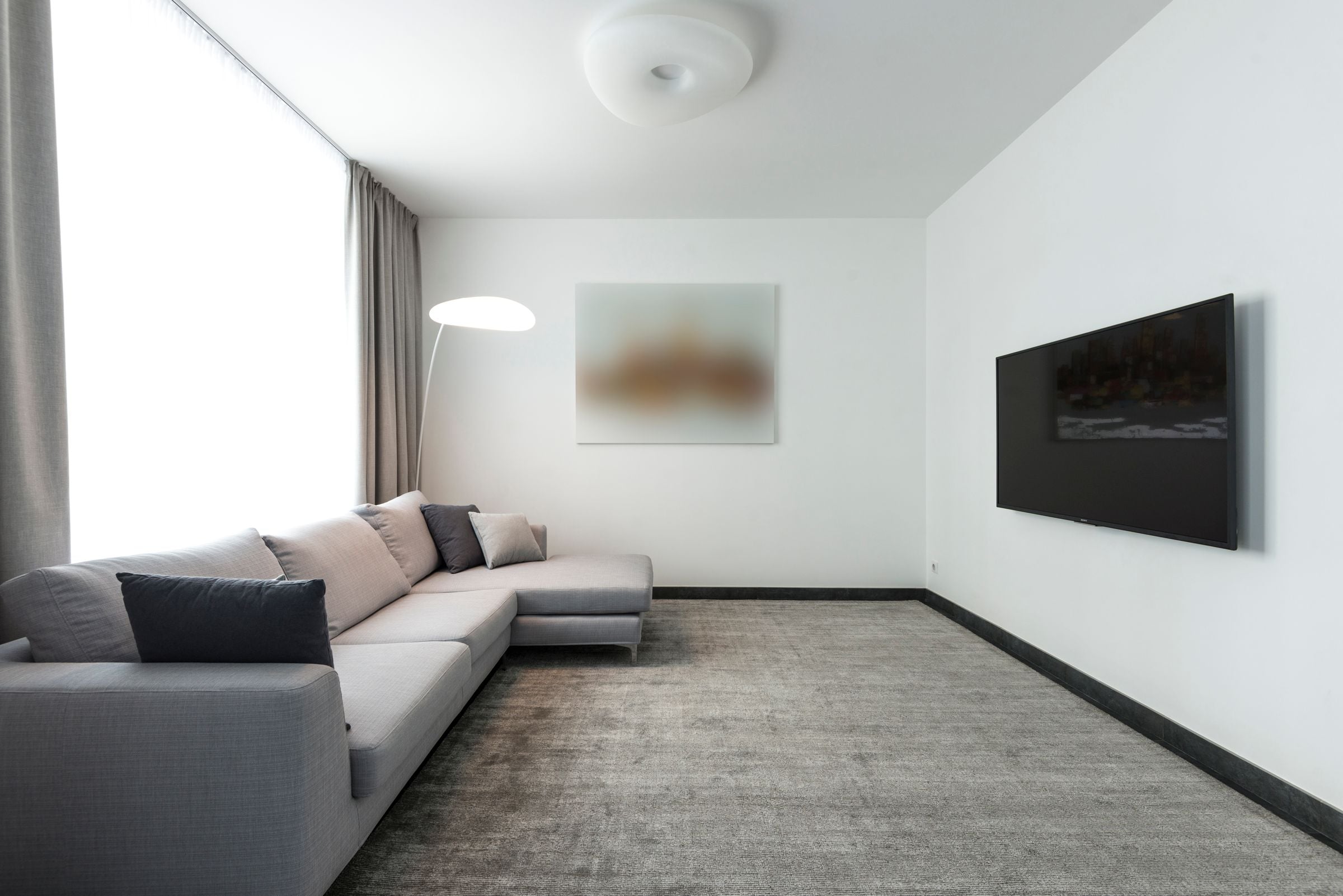 Contemporary living room with a gray sectional sofa and a wall-mounted TV.
