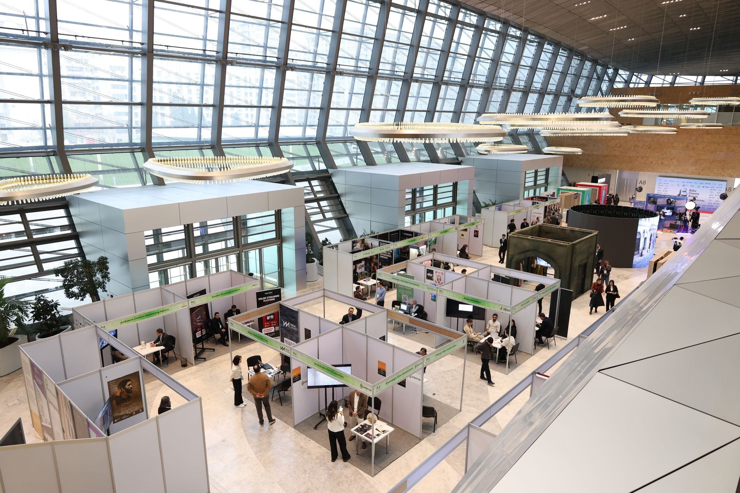 A bustling trade show exhibition inside a modern hall with people networking and exploring booths.