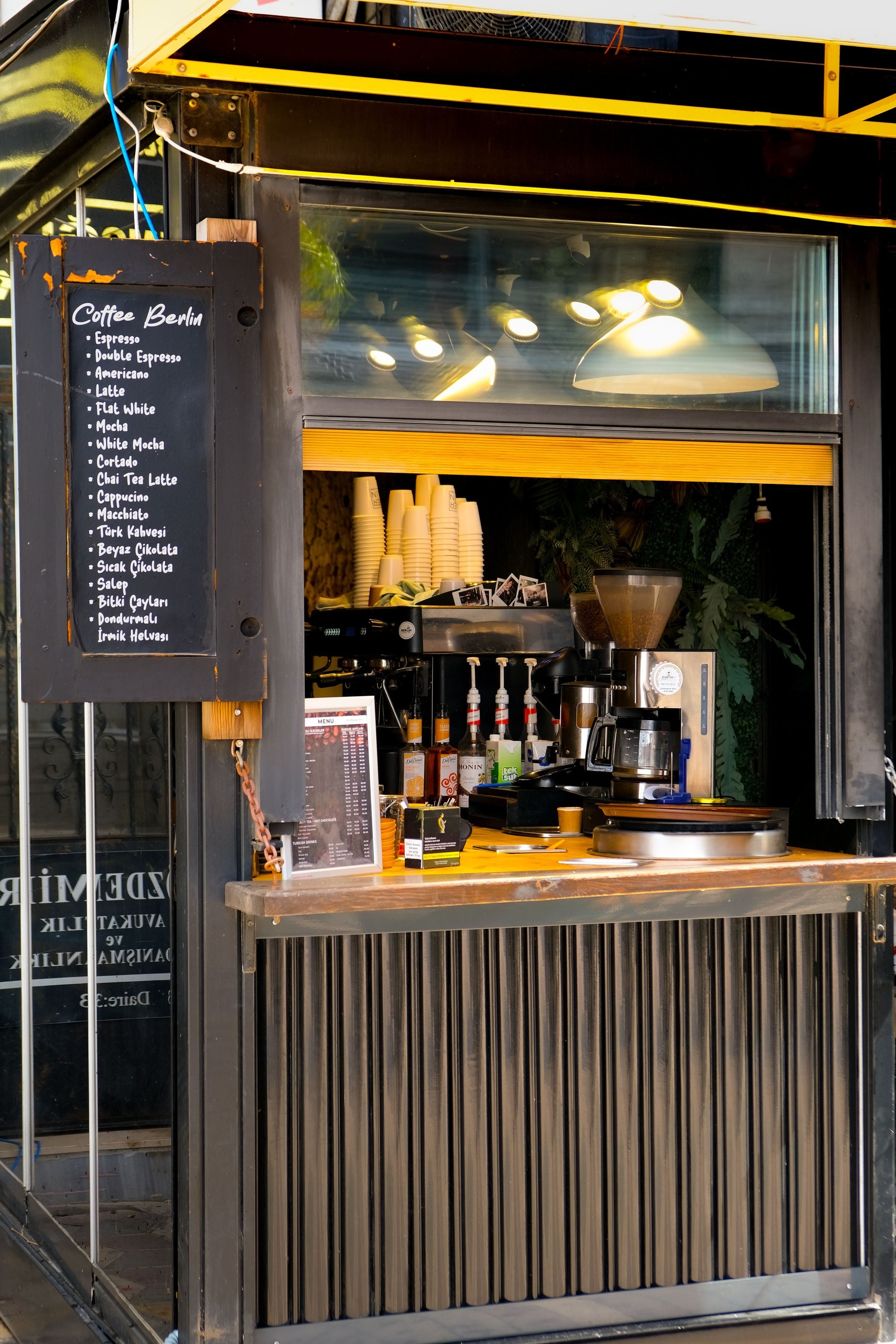 Small coffee bar kiosk with menu displaying espresso options and cozy atmosphere.