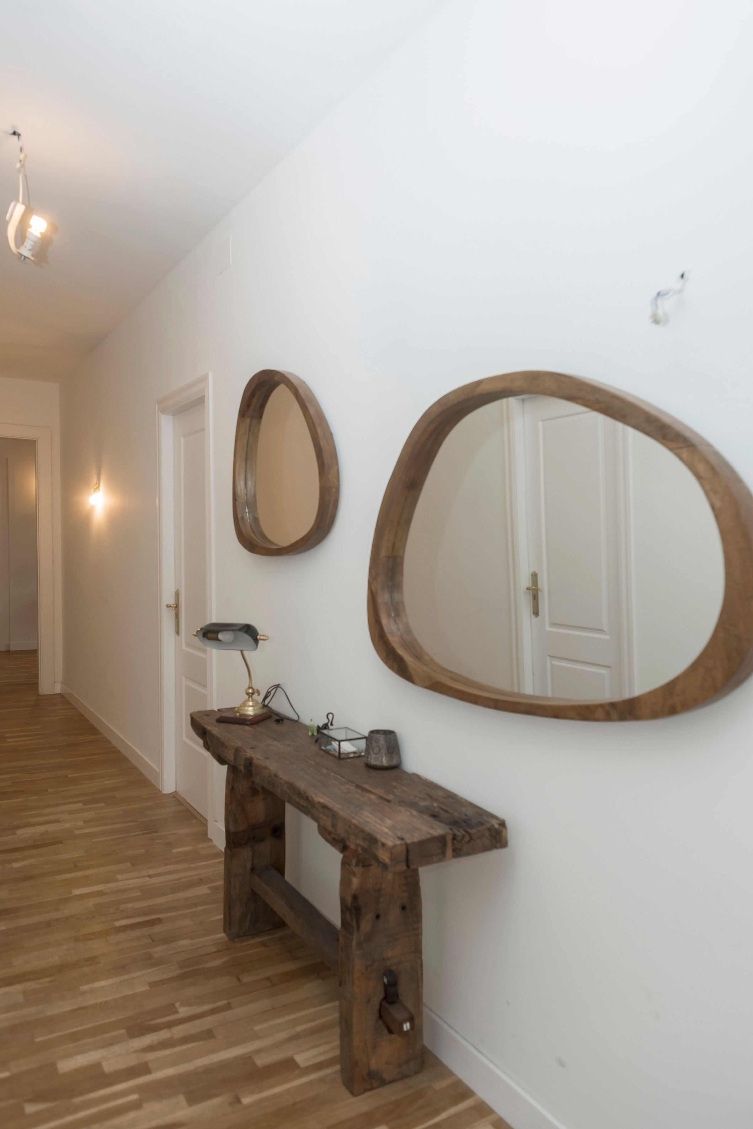 Stylish hallway with wooden mirrors and console table on white walls.